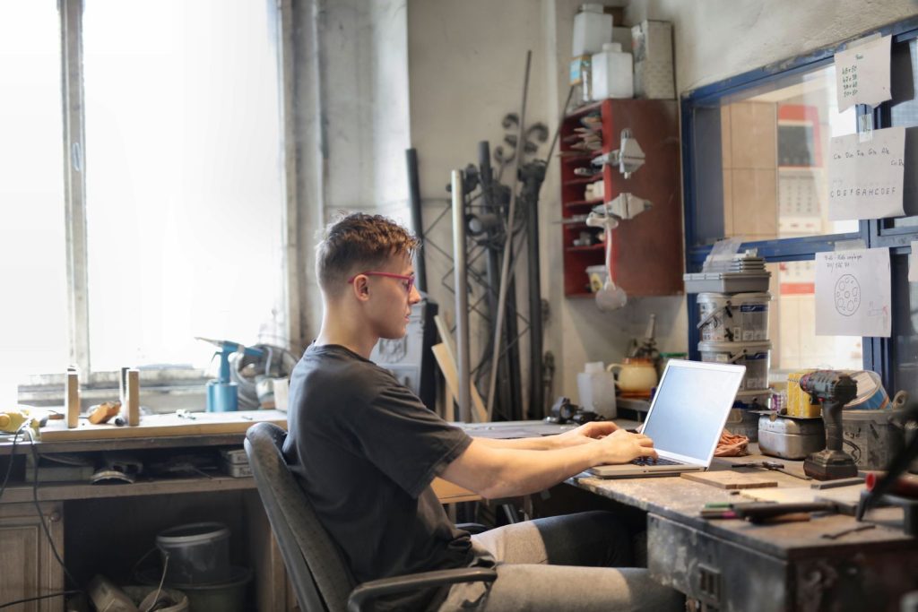 Vakman werkt op zijn laptop te midden van gereedschap in zijn werkplaats