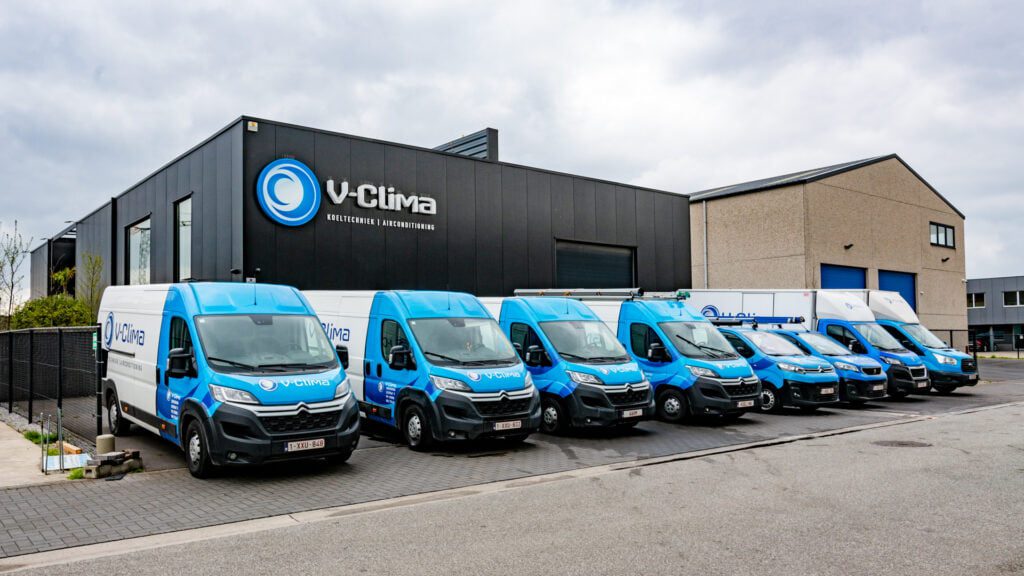 Het pand van V-Clima in Stekene met een rij blauwe bestelwagens voor de deur