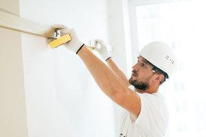 Aannemer meet een muur op met een waterpas op een bouwwerf, illustratie bij artikel over website laten maken voor aannemers
