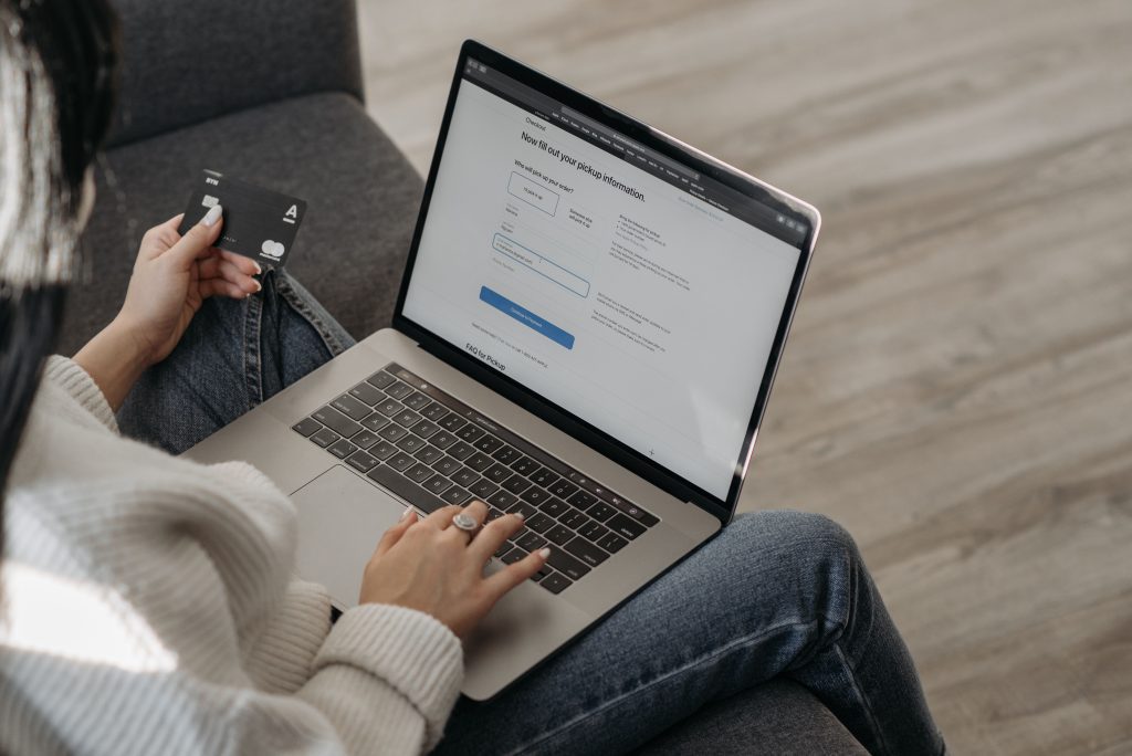 Klant vult op een laptop haar gegevens in om online te boeken en houdt daarbij haar bankkaart in de hand