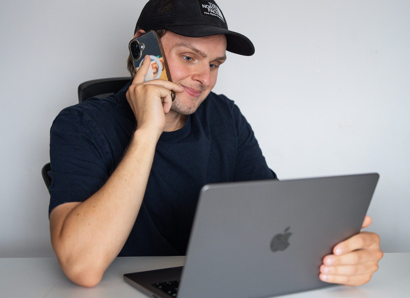 Silvio, webdesigner uit het Waasland, belt met een klant terwijl hij meekijkt op zijn MacBook