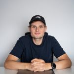 Silvio, zelfstandig webdesigner, zit aan een bureau met een laptop en kijkt recht in de camera voor een persoonlijke introductie op zijn website.